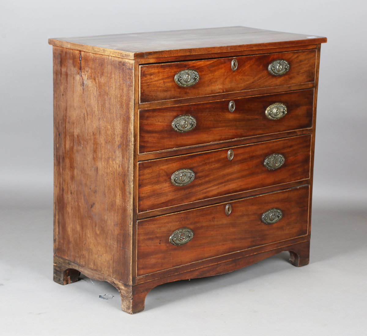 A George III mahogany chest of four graduated long drawers, fitted with oval embossed brass