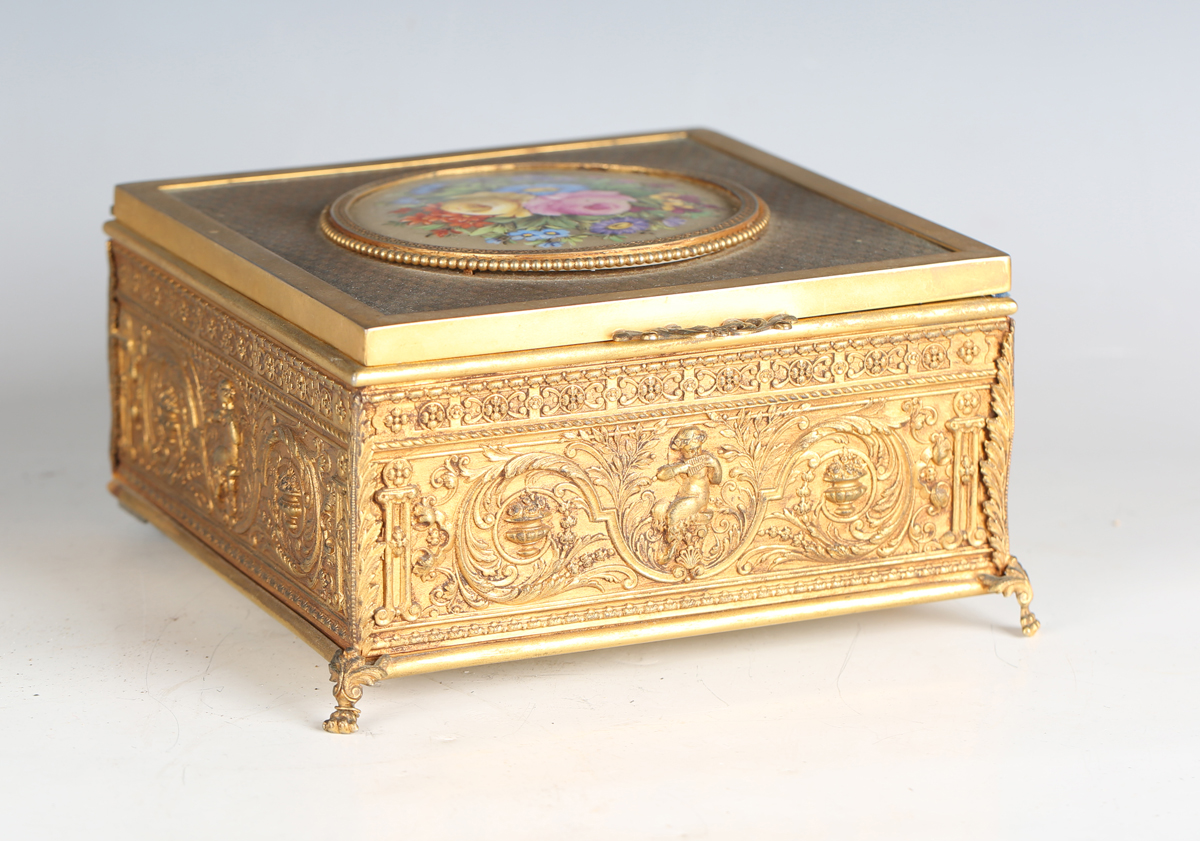 An early 20th century French gilt metal jewellery casket, the top inset with a floral painted