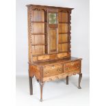 An 18th century and later oak dresser, the later shelf back fitted with a clock movement, the base