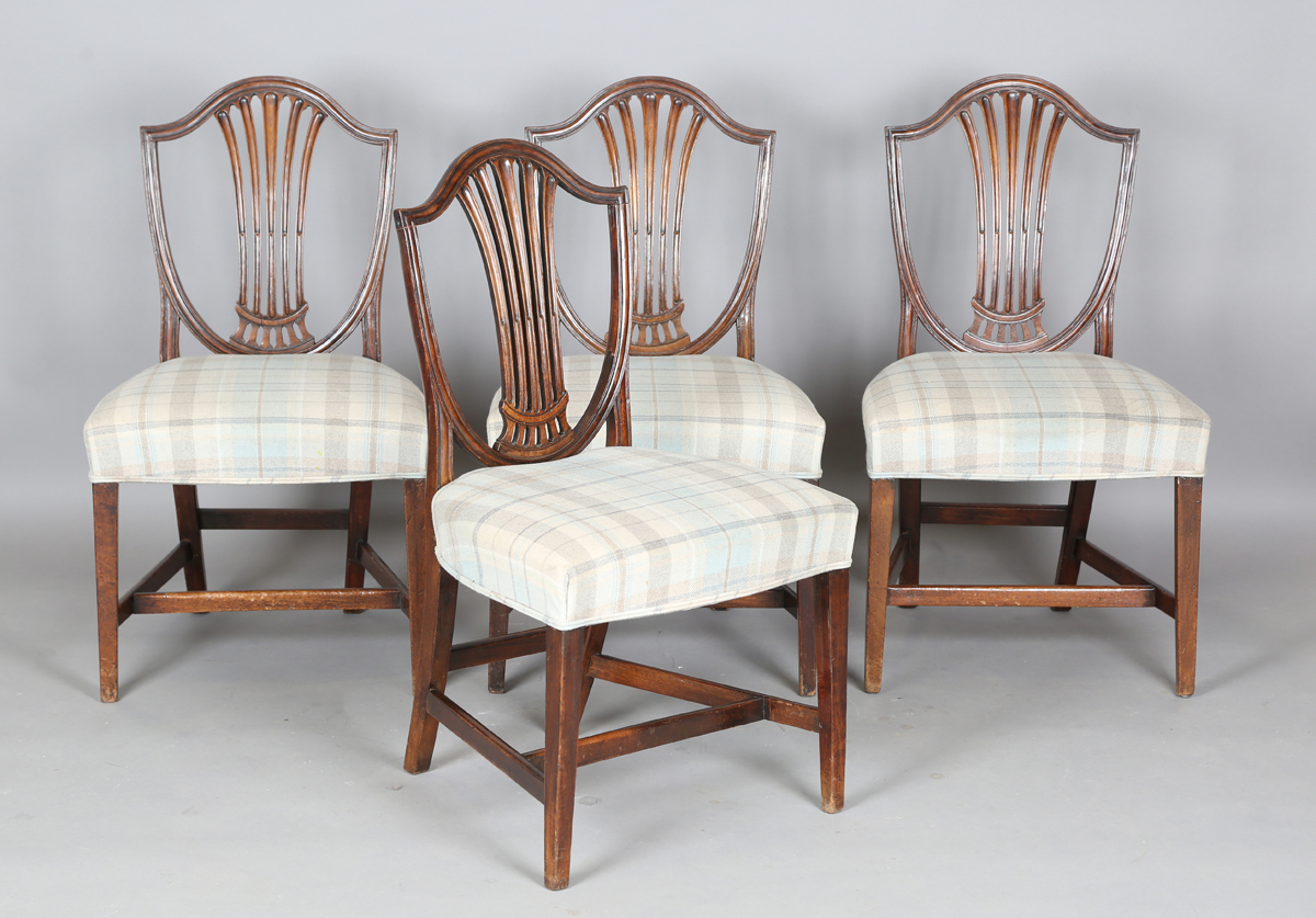 A set of four George III mahogany dining chairs with pierced splat backs and overstuffed seats,