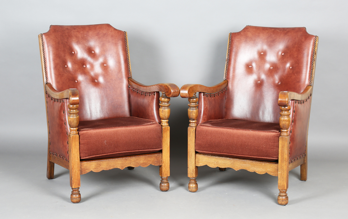 A pair of early/mid-20th century oak framed armchairs, upholstered in buttoned brown leatherette,