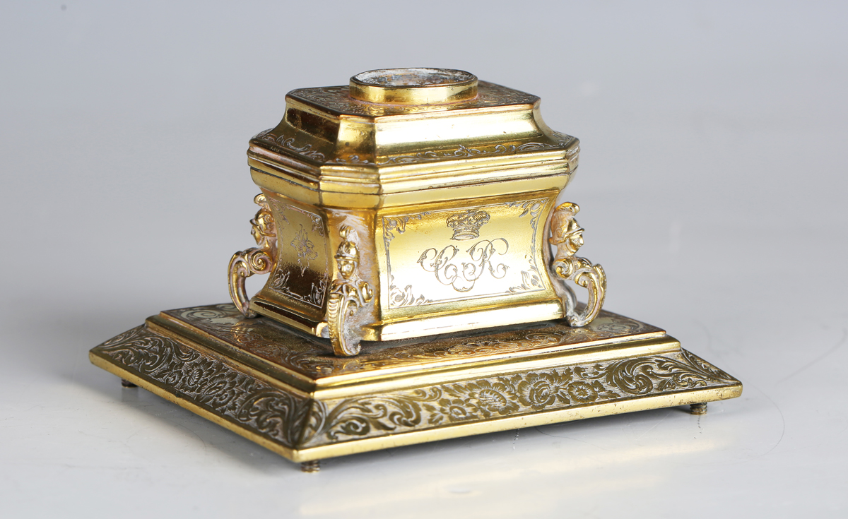 An early 19th century gilt metal inkwell of sarcophagus form, engraved with floral bands and