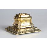 An early 19th century gilt metal inkwell of sarcophagus form, engraved with floral bands and