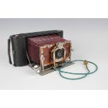 An early 20th century folding camera with burgundy leather bellows and silvered and gilt brass