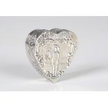 A late Victorian silver heart shaped box, the hinged lid embossed with an exterior scene and a man