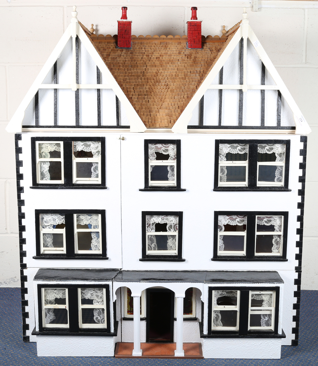 A 20th century Tudor style doll's house, the double-gabled tiled roof above a double opening front