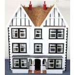 A 20th century Tudor style doll's house, the double-gabled tiled roof above a double opening front