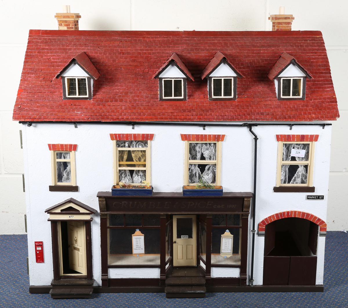 A doll's house baker's shop 'Crumble & Spice', the hinged dormer roof revealing a landing and two