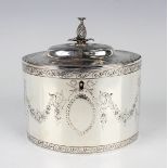A George III silver oval tea caddy, the hinged lid with pineapple finial above engraved floral