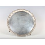 A late Victorian silver circular card salver with raised gadrooned rim, on scroll legs terminating