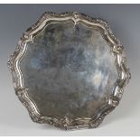 A George V silver circular salver, the cast raised wavy reeded rim with strapwork and scallop