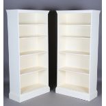 A pair of 20th century white painted open bookcases with dentil moulded pediments above four fixed