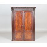 A George III Chippendale period figured mahogany hanging corner cabinet, the blind fretwork frieze