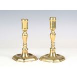 A pair of early 18th century brass candlesticks with baluster stems and canted square bases,