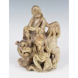 A Chinese carved soapstone figure group, late Qing dynasty, modelled as a luohan seated on the