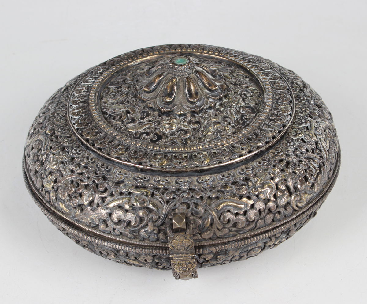 A South-east Asian white metal and parcel gilt circular box and cover, probably Tibetan or Chinese