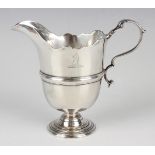 A George II Irish silver cream jug of girdled helmet form with shaped rim and scroll handle, on a