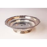 An Edwardian silver circular basket with pierced sides within a wavy gadrooned rim, raised on a