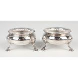 A pair of late Victorian silver circular salts with gadrooned rims, on stylized scallop shell