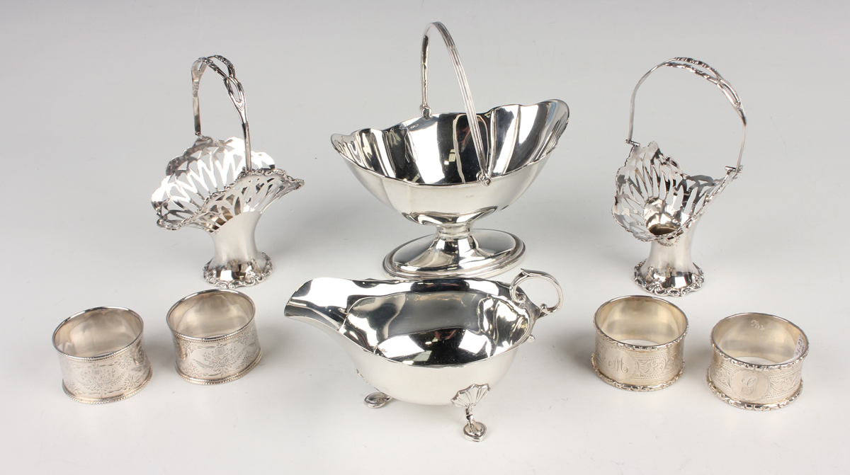 A pair of George V silver swing handled posy baskets, each pierced and cast with scrolls, Chester