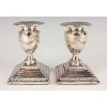 A pair of Elizabeth II silver candlesticks, each with detachable nozzle and ribbon swag