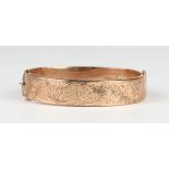 A 9ct gold oval hinged bangle, the front with feathered scroll engraved decoration, Birmingham 1920,