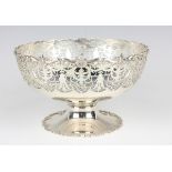 A George V silver circular footed bowl with cast scallop shell and scroll rim above pierced scroll