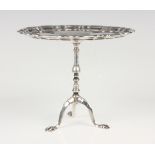 An Edwardian silver novelty bonbon tazza in the form of a wine table, the circular top with piecrust