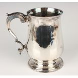 A George III silver tankard of baluster form with foliate capped scroll handle, on a stepped