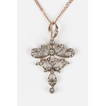 A late Victorian gold, silver and diamond pendant in an openwork scrolling design with a diamond set