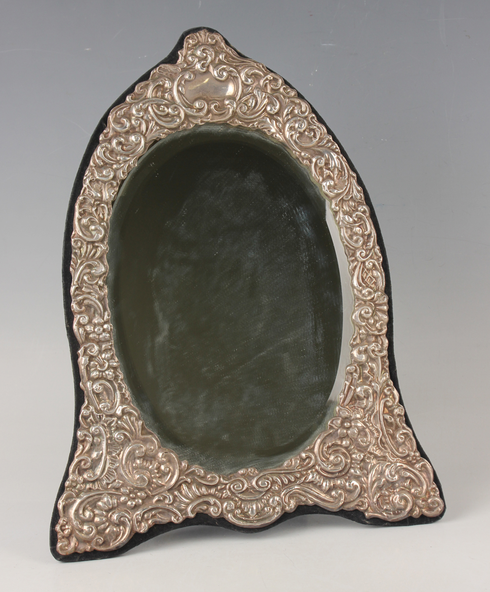 An Elizabeth II silver mounted dressing table mirror of shaped oval form, embossed with flowers