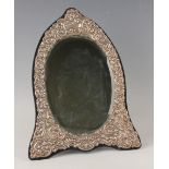 An Elizabeth II silver mounted dressing table mirror of shaped oval form, embossed with flowers