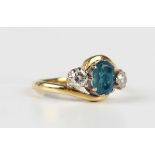 An 18ct gold ring, claw set with an oval cut treated dark blue topaz between two circular cut