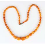 A single row necklace of fifty-one graduated oval varicoloured butterscotch coloured opaque and