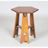 An early 20th century Arts and Crafts oak hexagonal occasional table, raised on three pierced