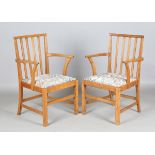 A pair of mid-20th century Arts and Crafts style oak comb back elbow chairs, designed by Edward