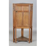 An early 20th century Arts and Crafts oak floor-standing corner cabinet, in the manner of Heals, the