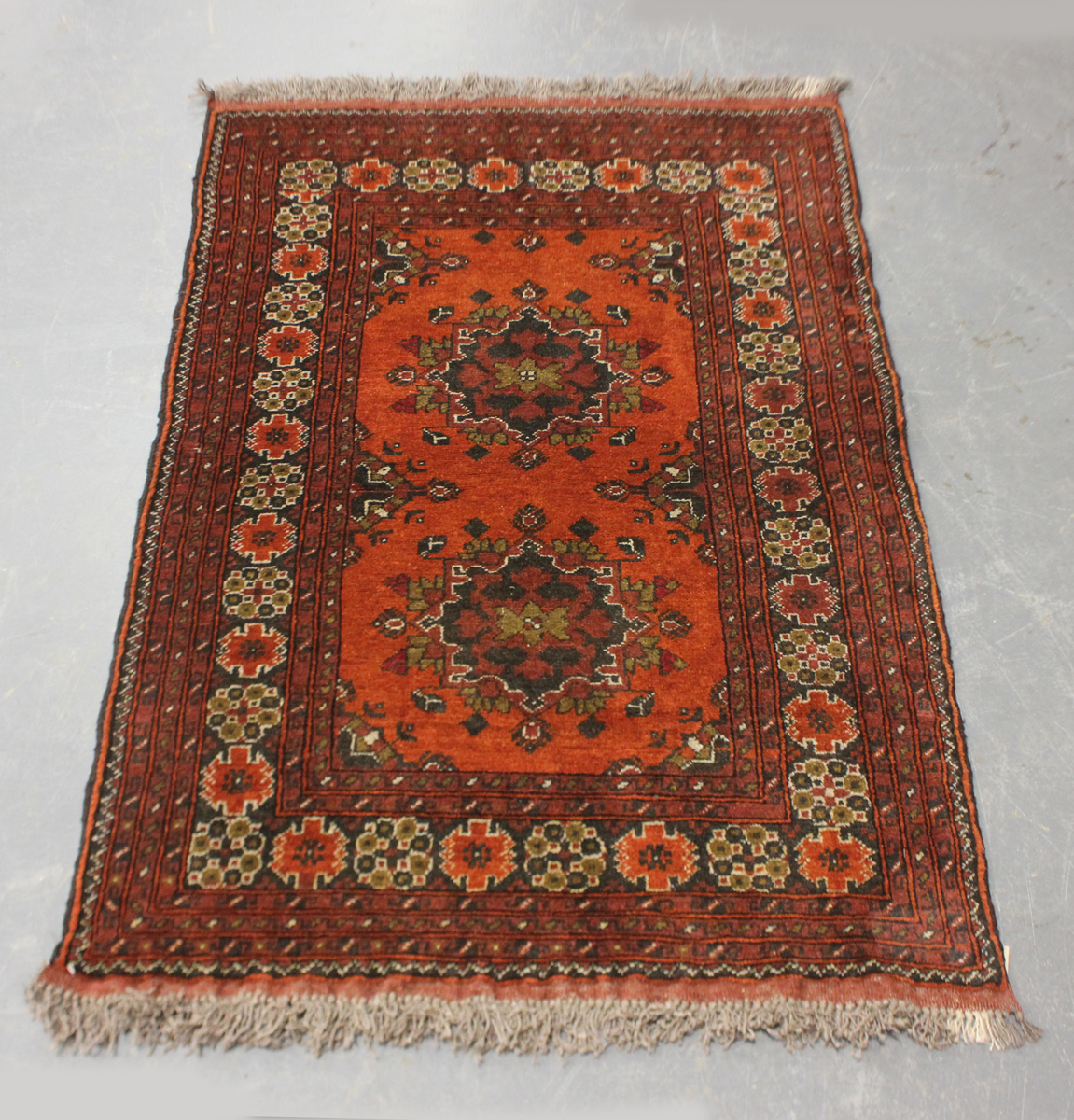 A small Afghan rug, modern, the terracotta field with two medallions, 144cm x 96cm.Buyer’s Premium