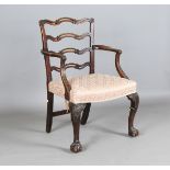An early 20th century George III style mahogany framed pierced ladder back elbow chair with carved