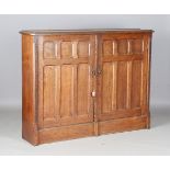 A late Victorian Gothic Revival oak side cabinet, the two chamfered panel doors enclosing a