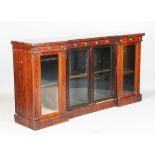 An early 19th century rosewood inverted breakfront side cabinet, the frieze with applied roundel