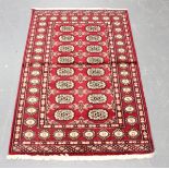 A Pakistan bokhara rug, modern, the claret field with two columns of guls, within a sunburst gul