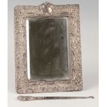 An Edwardian silver mounted rectangular dressing table mirror, embossed with flowers and scrolls,