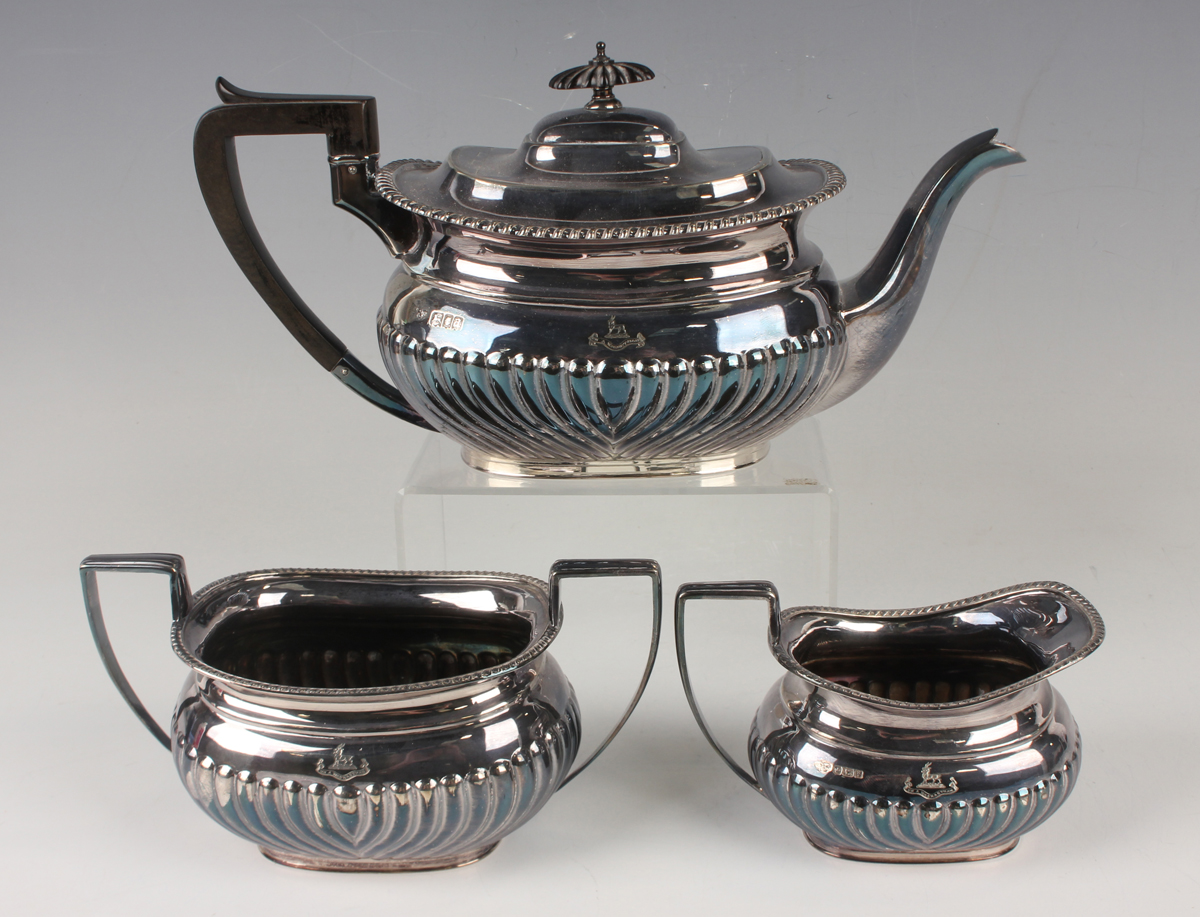 A George V silver three-piece tea set of half-reeded cushion form, comprising teapot, two-handled