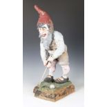 An early/mid-20th century composite terracotta garden gnome, playing golf, height 75cm (faults).