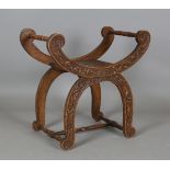 An early 20th century oak window seat of 'X' framed form, profusely carved with foliage, height