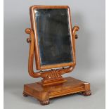 A William IV figured mahogany swing frame mirror with a carved scroll support and inverted