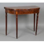 A George III mahogany fold-over card table with satinwood crossbanding and reeded tapering legs,