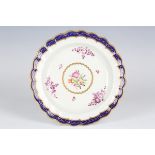 A Worcester plate, circa 1775, of lobed form, painted with a central polychrome medallion of