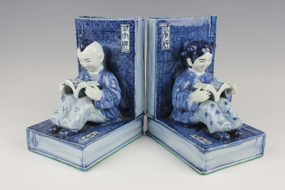 A pair of Chinese blue and white porcelain bookends, each modelled with a seated boy or girl reading